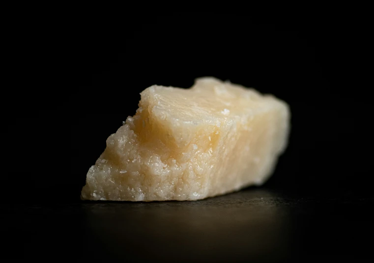 a piece of yellow rock sitting on top of a black surface