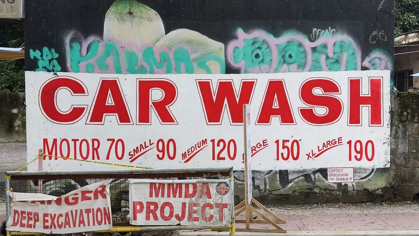 a sign in front of a car wash covered in graffiti