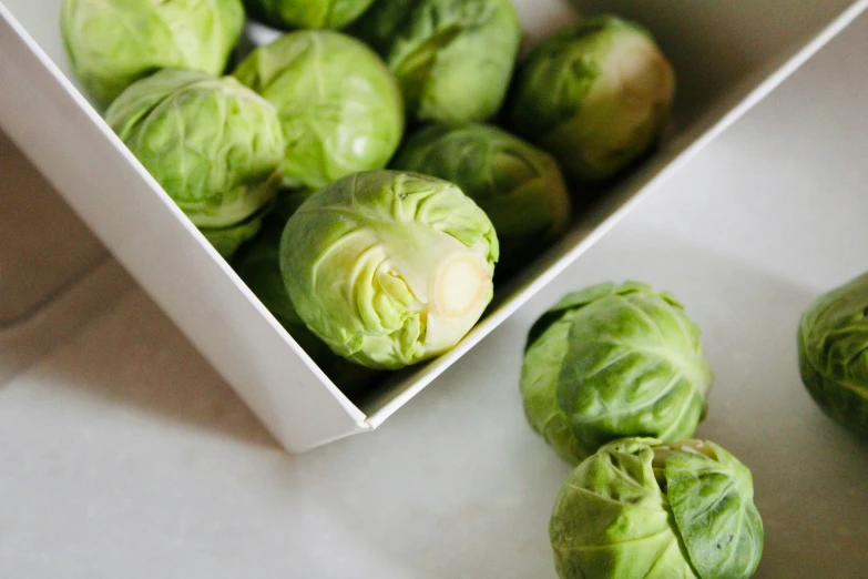 a white box full of brussels sprouts next to each other
