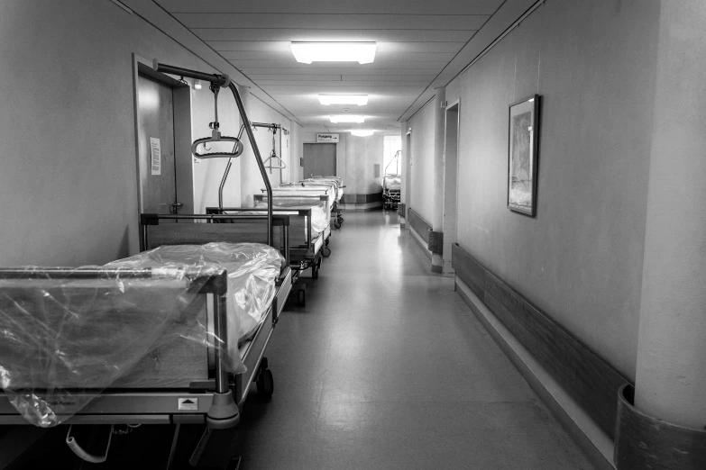 empty hospital beds line the corridor between a corridor