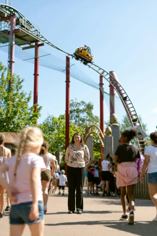 a woman in pink shirt standing near roller coaster