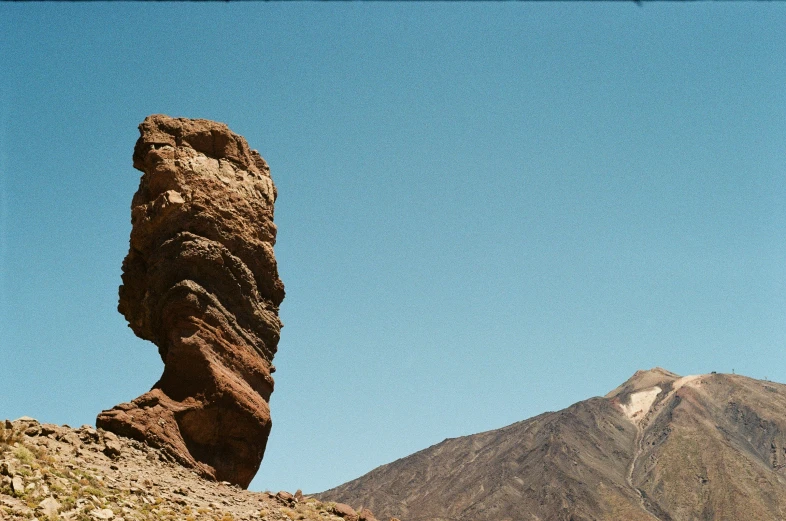 a tall rock with a large piece of stone on top of it