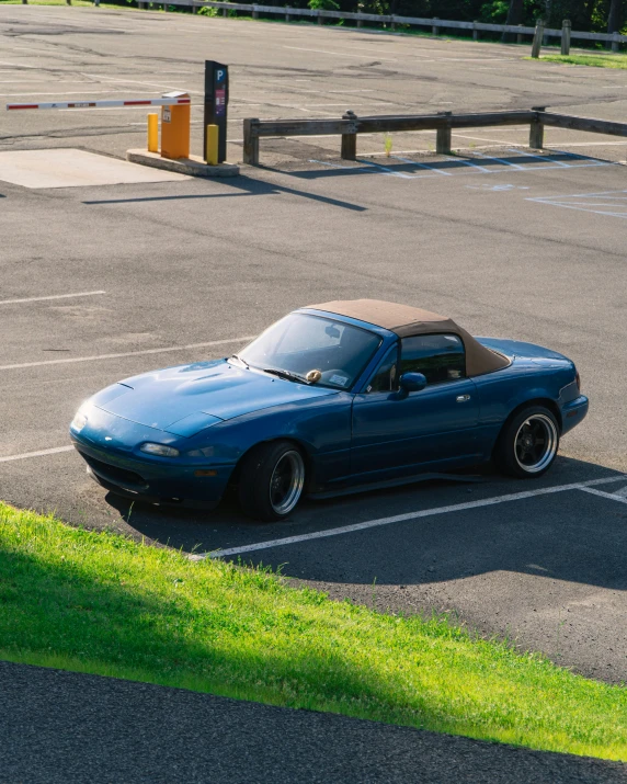 a blue convertible car parked on the side of a parking lot