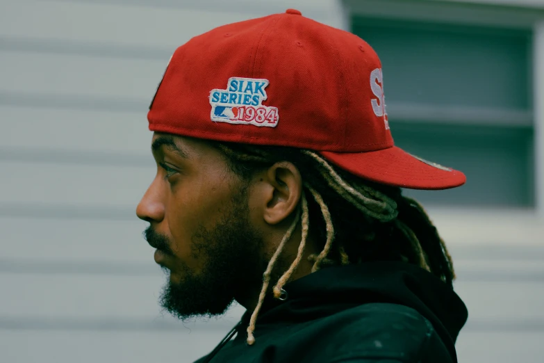 a person with dreads wearing a red hat