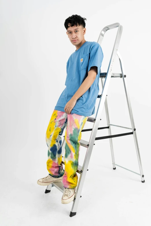 a boy posing for a po in the camera while leaning against a ladder