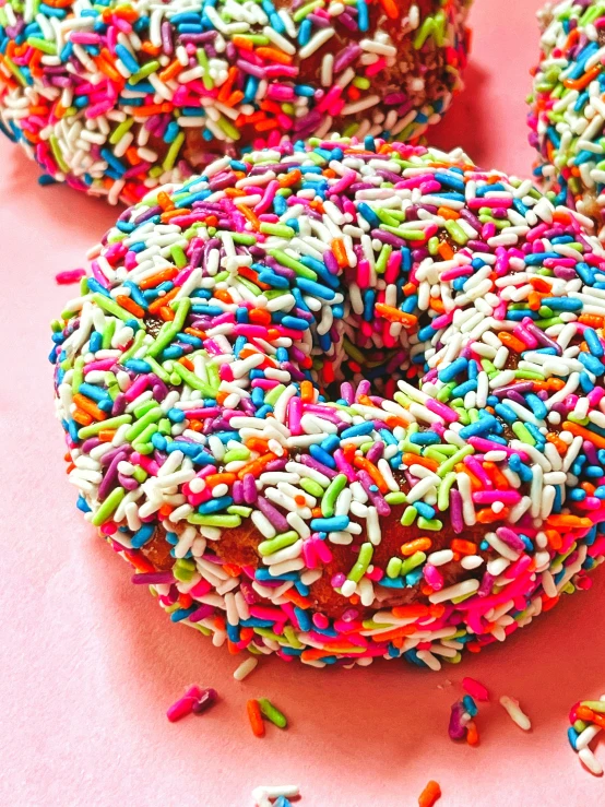 a pink table topped with lots of donuts and sprinkles