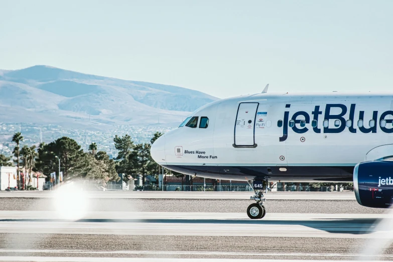 a jet blue airplane sitting on a runway at an airport