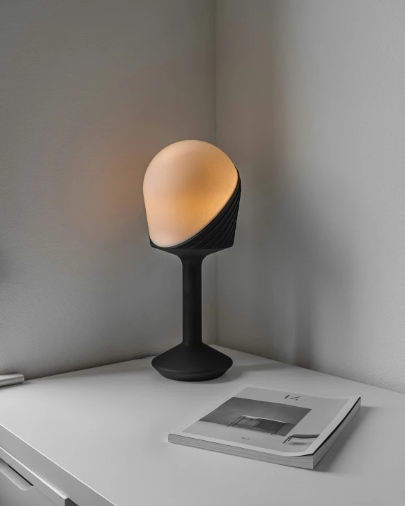 an electronic lamp sits on a desk next to a book