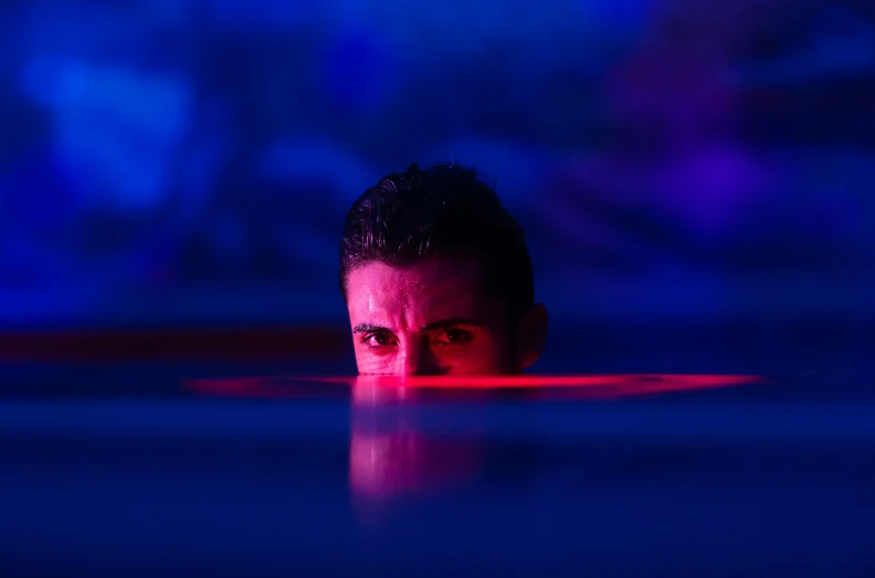 a man hiding underneath a table with a blue and red background