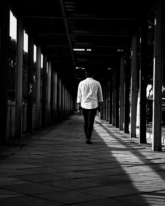 a man walks beneath a canopy as the sun is seen