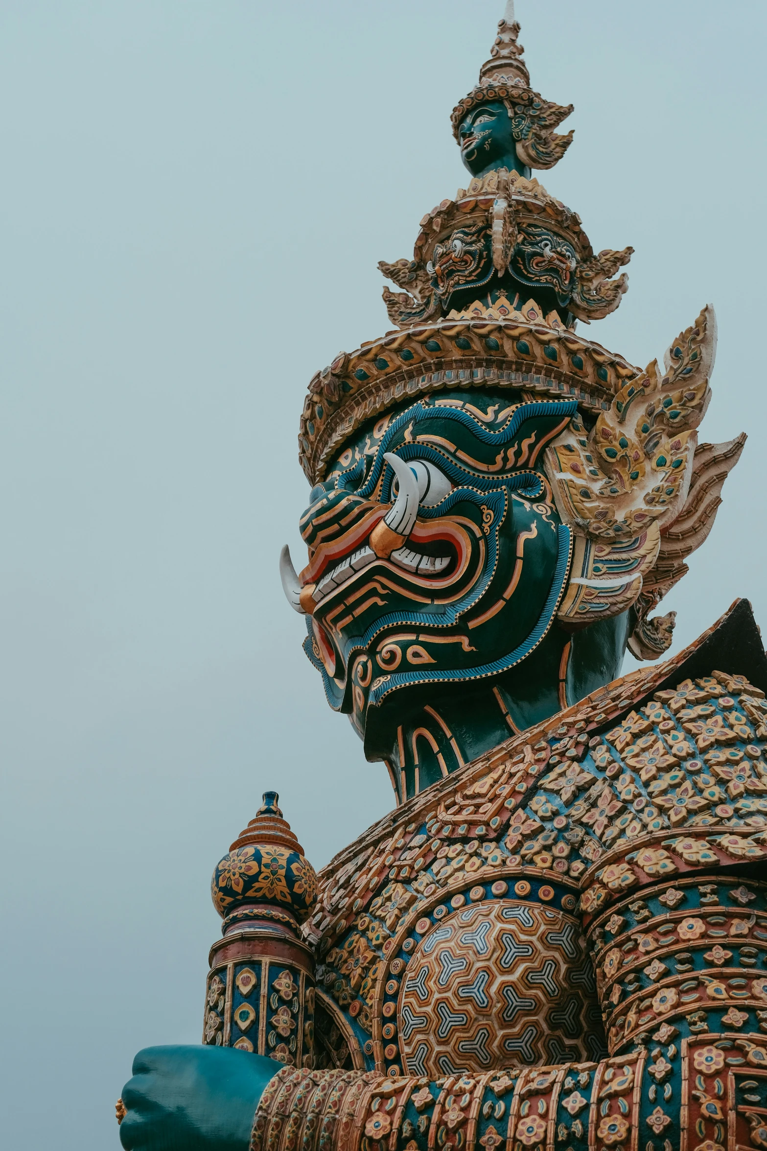 an elaborate statue against a gray sky with a blue background