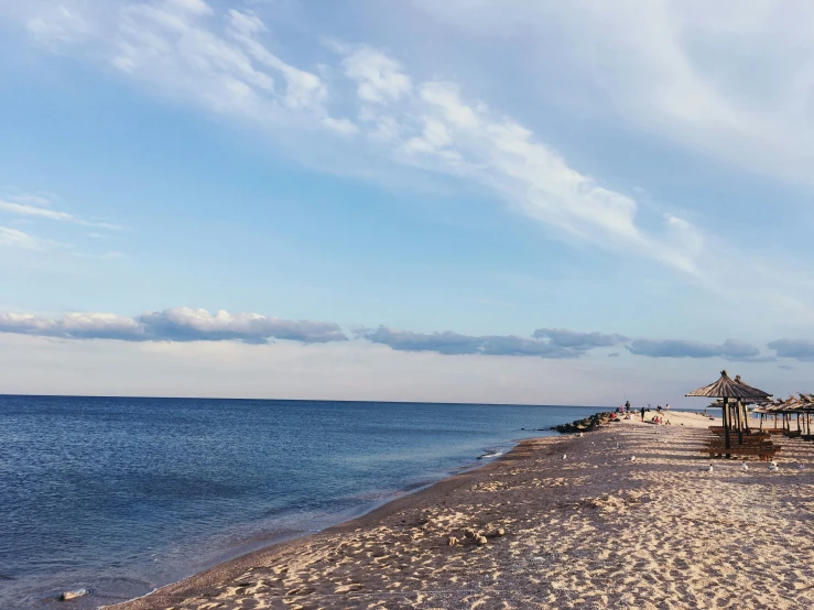 some kind of beautiful beach with blue water and a long line of umbrellas