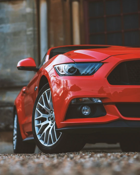 a red mustang parked in front of a garage