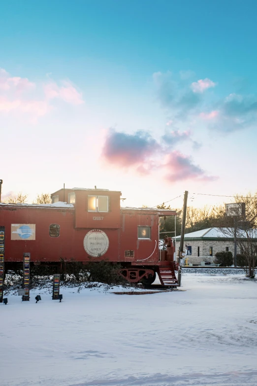 a red train that is sitting on a snowy day