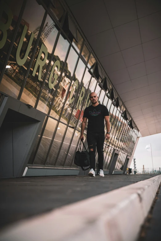 a man with his luggage stands at the entrance to a glass building