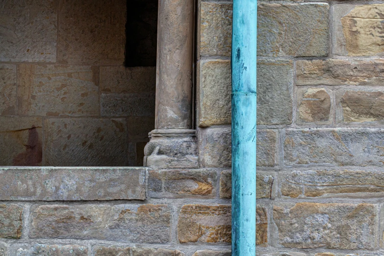 a metal pole between two windows next to a blue pipe