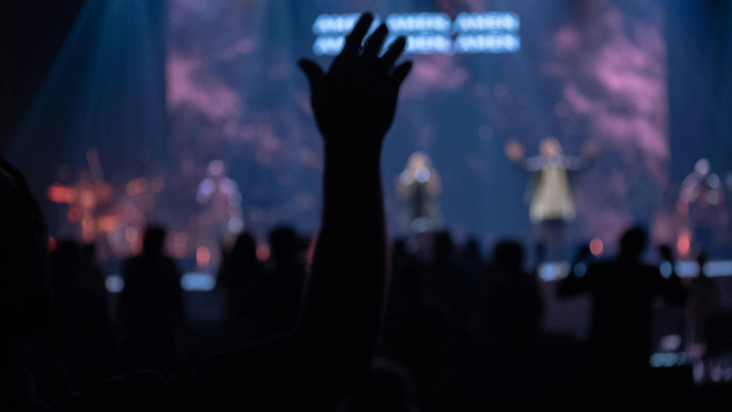 a concert with the crowd waving and people clapping in front