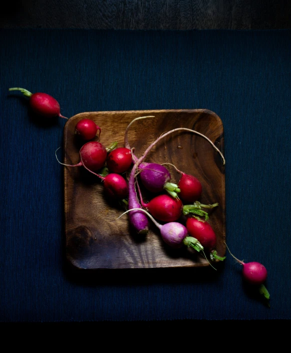 radishes and carrots on a square wooden  board