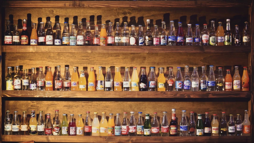 a wooden shelf with many glass bottles and labels