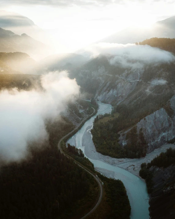 a river cuts through the valley under clouds