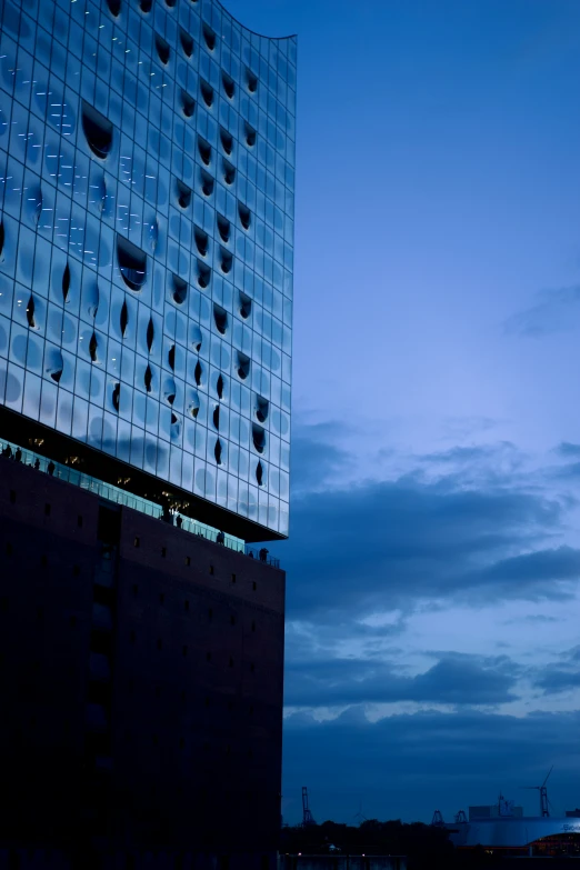 a clock tower in front of a large blue building at night