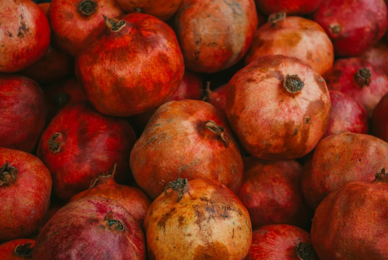 a large pile of pomegranates with some rotten inside