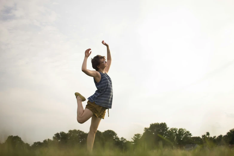 a woman in blue shirt and brown shorts playing with a green frisbee