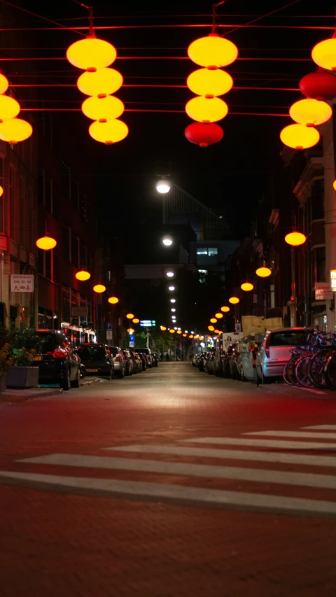 several bright yellow lights hang over an empty city street