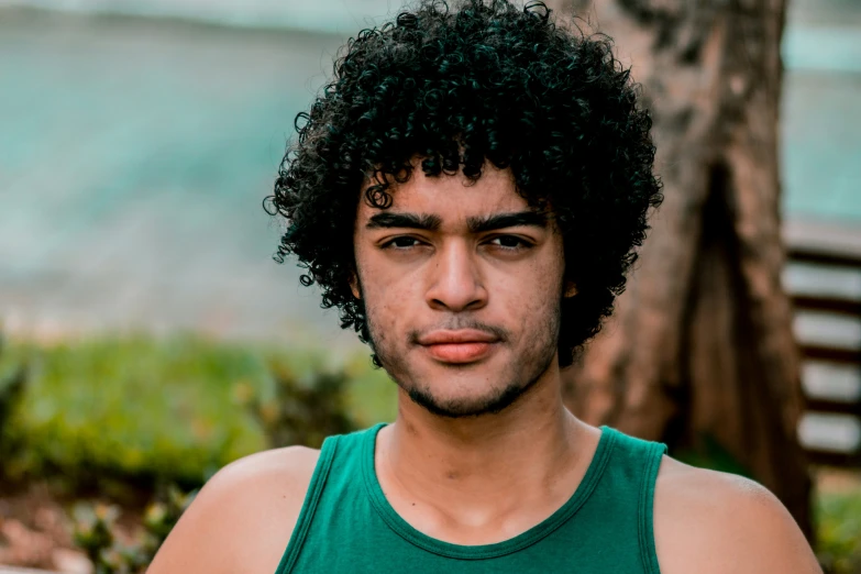 the young man with a very big black afro is in front of a tree