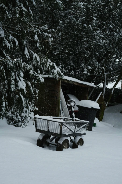 a wagon sits on the snow covered ground outside a house