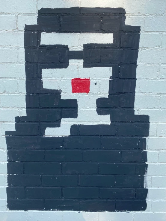 black bricked wall with a red square painted on the side