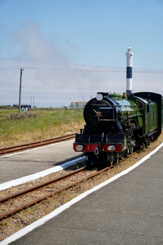 a black train engine sitting on the tracks next to grass and trees