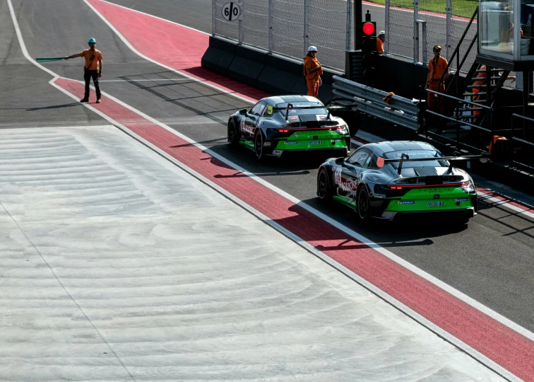 two cars on a race track with people in the background