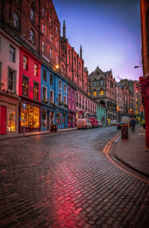 a street is surrounded by colorful buildings in the early evening