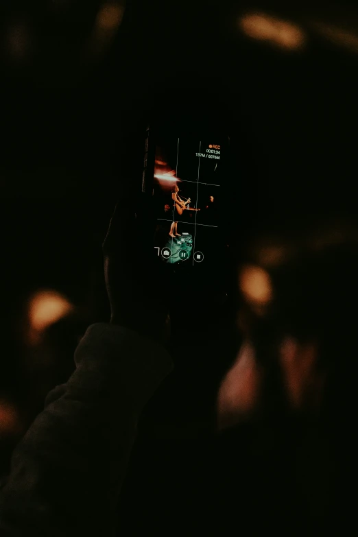 a person's hand in the dark holding up their cell phone