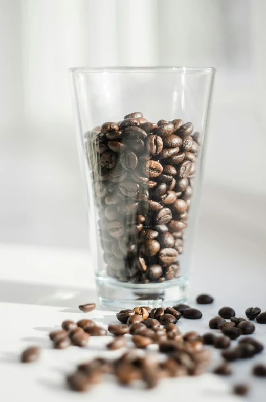 a glass filled with coffee beans sitting on top of a table