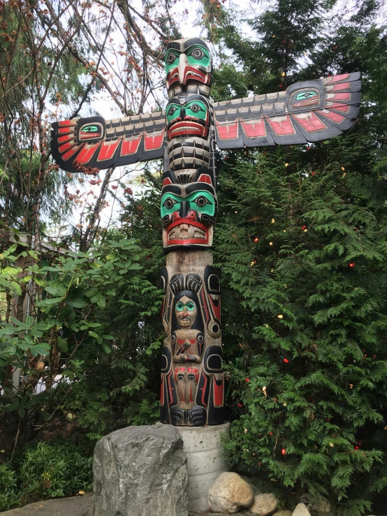 an intricately colored totema sits beside a green pine tree