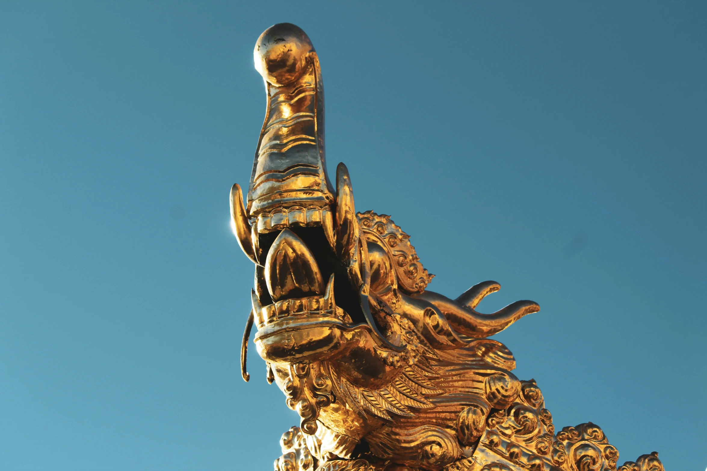 golden statue of demon holding a sword over its shoulder