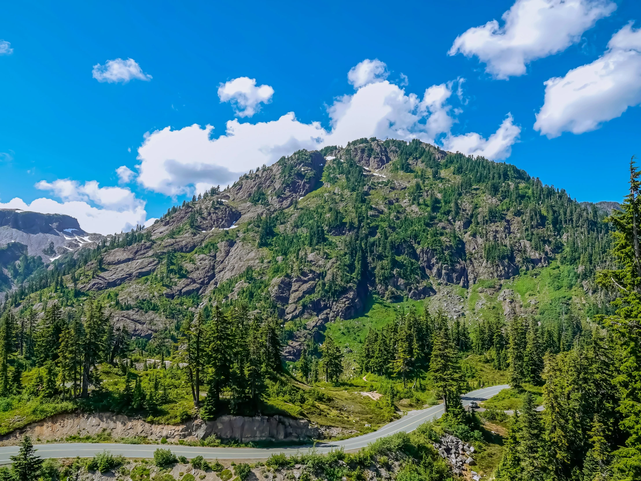 a winding road in the mountains next to trees