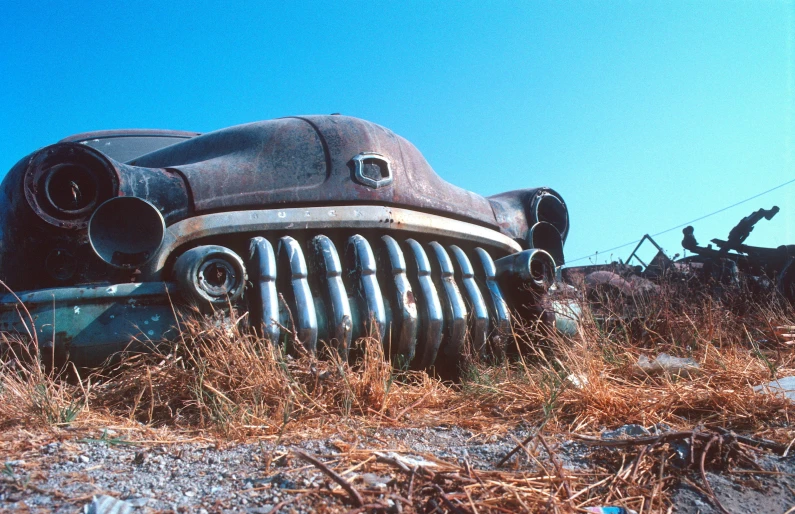 an old car sitting in the middle of some dirt