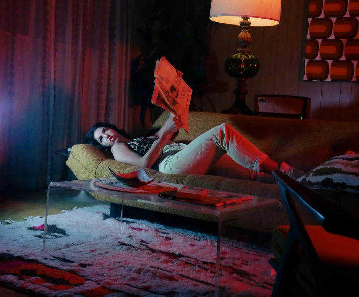 a woman laying on a couch holding up a red object