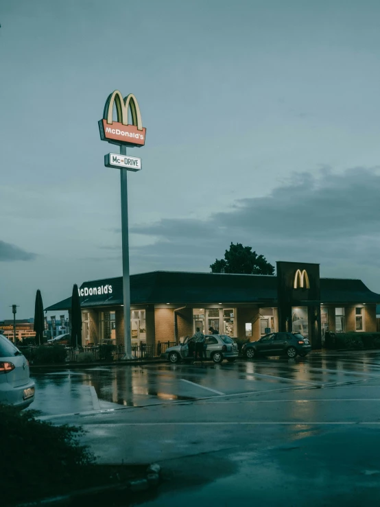 a rainy evening outside a mcdonald's and a car parked in front