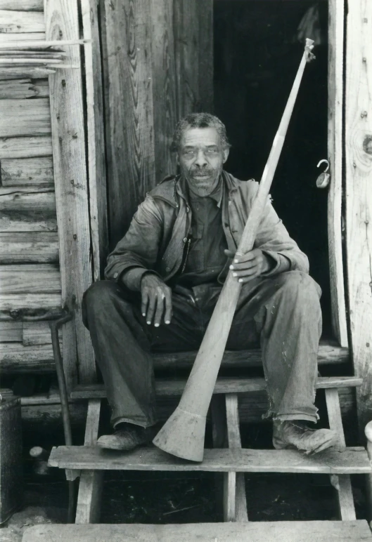 an old black and white po with man sitting on a step outside