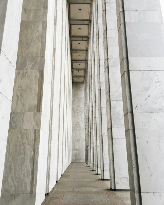 an empty walkway between two long white walls