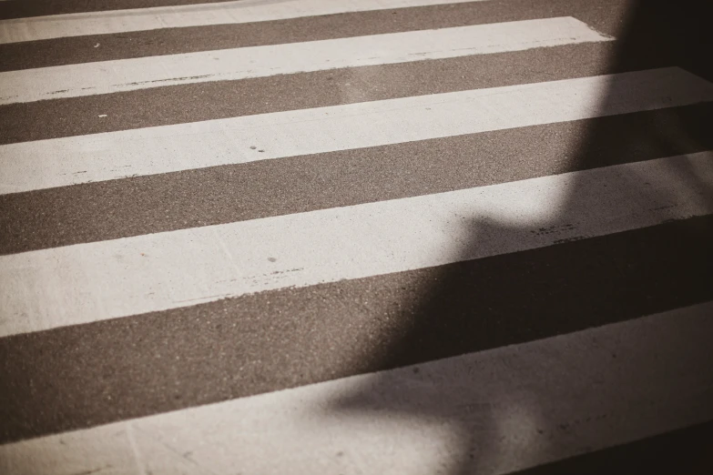 crosswalk with striped lines and the shadow of a person walking in it