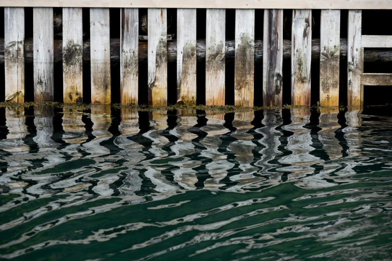 a wooden dock next to a lake with water under it