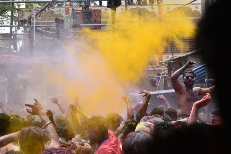 a crowd of people with their arms in the air spraying colored powder