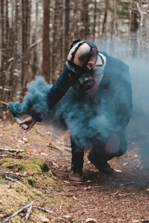 a man with protective gear bends down to smell smoke