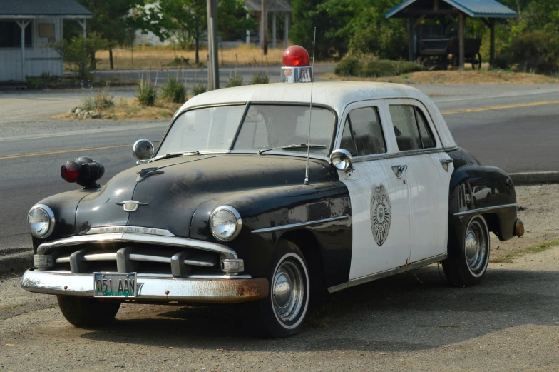 an old police car is sitting on the side of the road