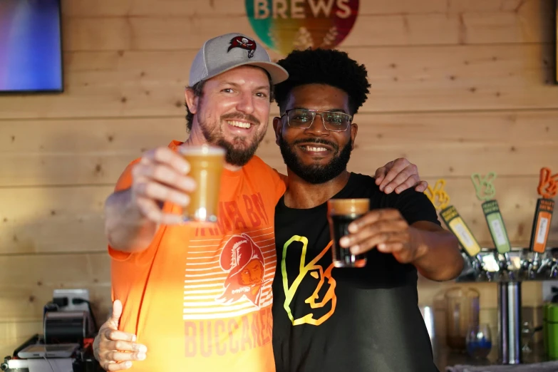 a man with glasses hugging another person in front of a bar